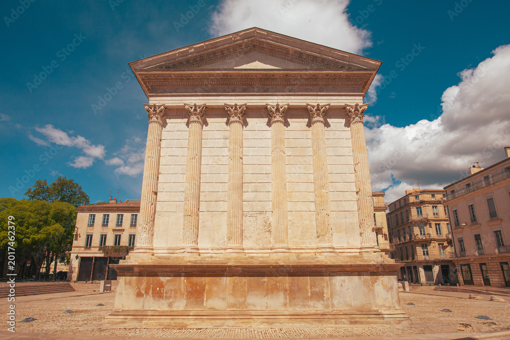 Fototapeta premium Hidden gems of France concept. Exterior of Maison Carree. Ancient Roman temple in Nimes. Outdoor shot. Sunny weather, cloudy sky