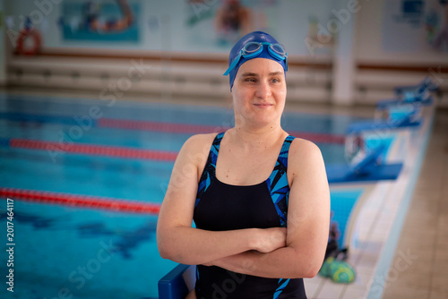 Visually impaired woman in swimsuit standing by the indoor swimming pool