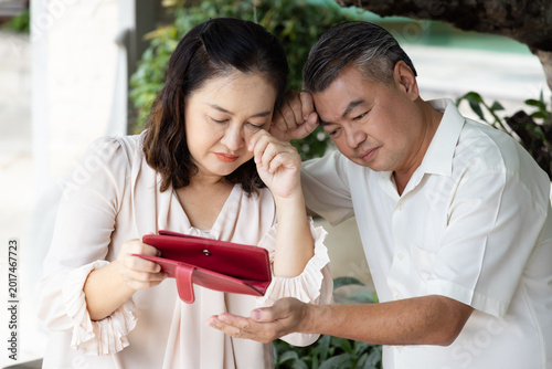 Poor sad crying Middle aged Asian couple having no money left, concept of no money, inflation, recession, joblessness, unemployment, financial problem, financial crisis, front view