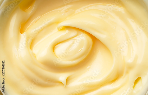 Creamy mayonnaise texture with soft swirls and glossy finish, macro top view of thick yellow sauce background