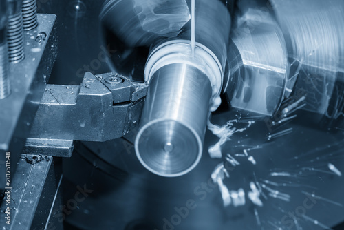 High-precision lathe machine finishing a metal shaft part using a liquid coolant method in a blue-toned scene.
