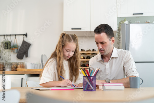 Foto Father helping daughter with drawing and homework sitting at kitchen table at ho