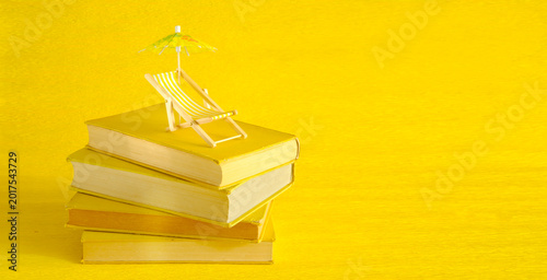 Quadro su tela stack of books with deckchair and sun umbrella, spring and summer holiday read