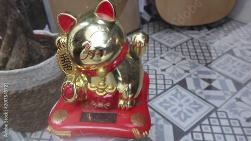 Solar-Powered Golden Maneki-Neko on Red Cushion.