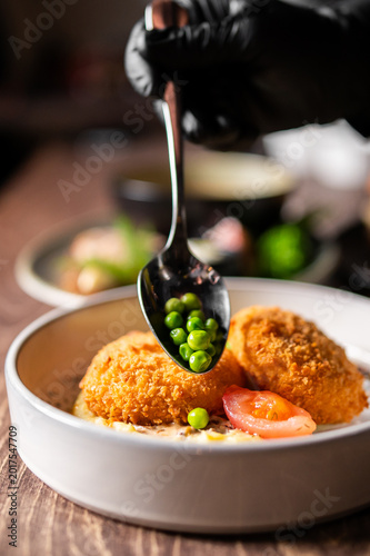 Foto A close-up shot of a chef's hand in a black glove using a spoon to garnish golde