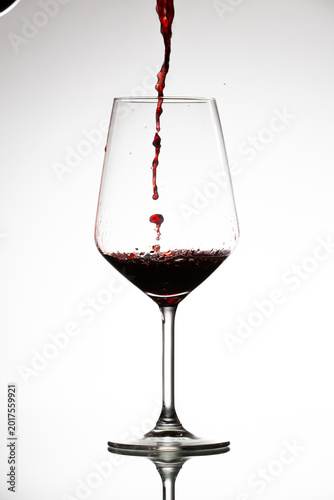 Фотография Red wine pouring into glass creating a splash