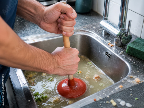 Man using plunger to unclog dirty kitchen sink