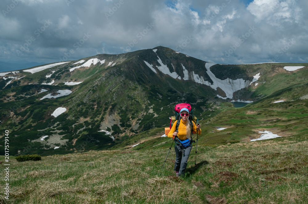 Fototapeta premium Female backpacker hiking near Lake Brebeneskul in the Carpathian Mountains through a dramatic alpine landscape. Adventure travel and wilderness trekking concept. Copy, empty space for text