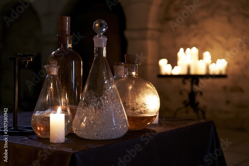 Vintage Laboratory Glassware with Lit Candles in Mysterious Dimly Lit Setting.