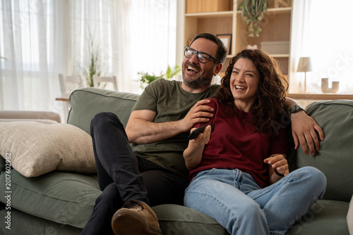 Smiling couple enjoying favorite TV series together on streaming at home