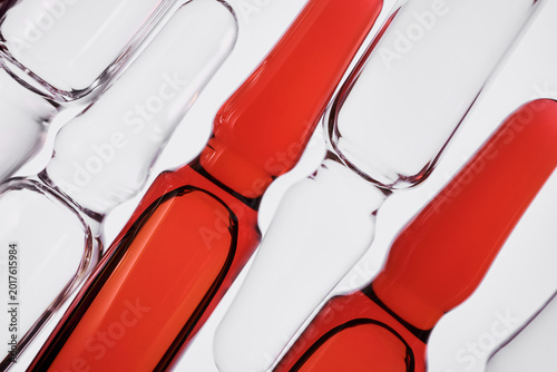 Medicine ampoules grouped together on white background, some filled with red liquid