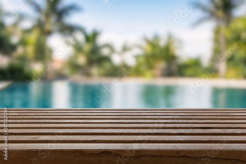 Wooden surface with tropical pool or beach in the background at day