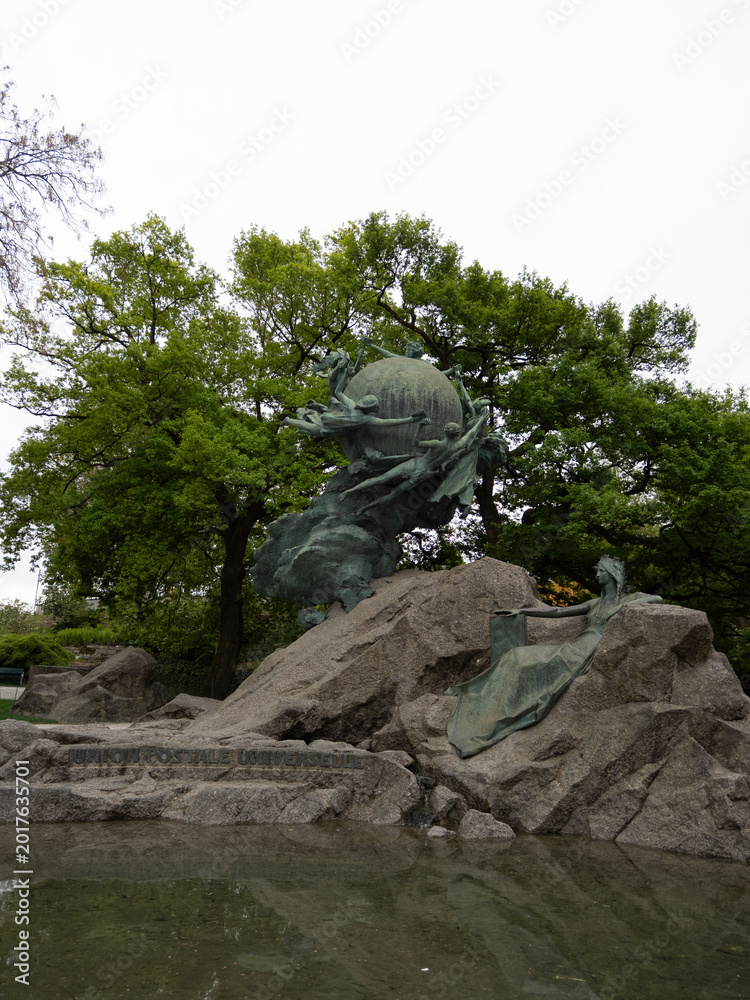 Fototapeta premium Weltpostdenkmal - allegorical bronze globe and reclining figure on rocky plinth in Bern park