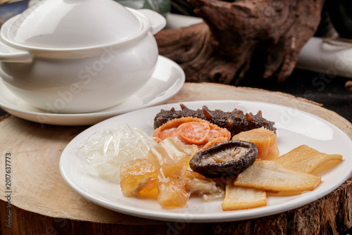 Obraz na płótnie The white porcelain tableware on the pine cutting board clattered against the rich seafood soup