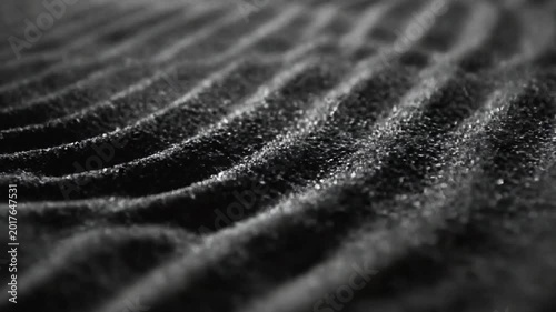 Dark sand dunes with wavy patterns and rugged texture on surface