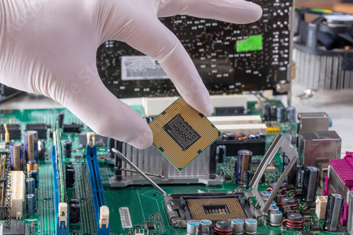 Technician hand holding processor above open motherboard socket during desktop PC assembly process