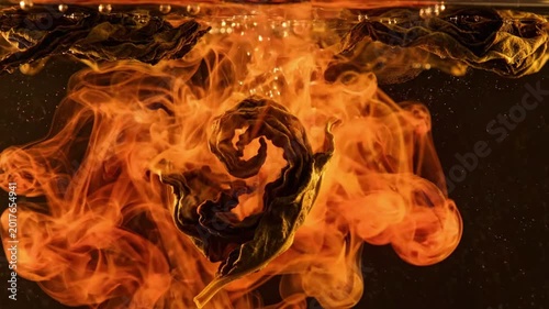 Dried tea leaf submerged in hot water, releasing vibrant orange pigment swirls and bubbles, creating abstract smoky patterns ideal for background or texture