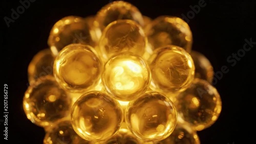 Abstract macro view of translucent golden spheres clustered together, illuminated from within, creating a glowing, organic molecular structure or bubble cluster