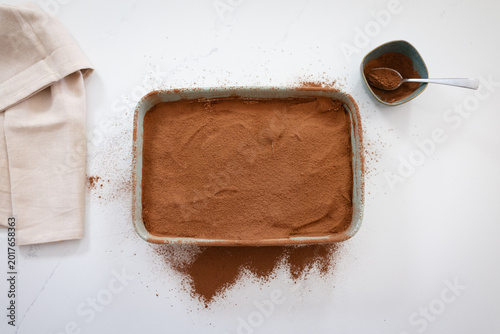 Принти на полотні Preparing delicious tiramisu dessert with cocoa powder topping