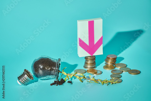 Fallen light bulb with sprout, euro coins and down arrow sticker on turquoise background, wasted innovation concept, copy space