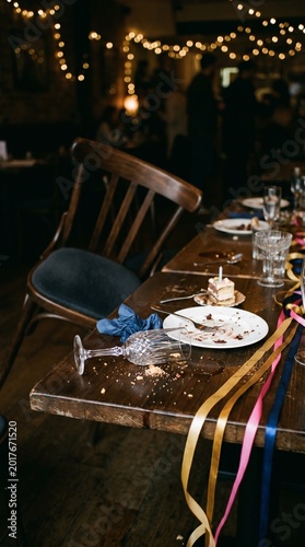 Empty party table with scattered plates and colorful ribbons  