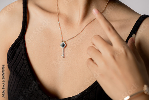 Close up beauty portrait featuring elegant key pendant necklace worn by woman in black outfit. Minimal luxury jewelry concept for fashion branding, feminine accessories, and modern lifestyle campaigns
