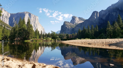 Yosemite Valley reflecting El Capitan and Cathedral Rocks in Merced River with pine trees and sandy riverbank