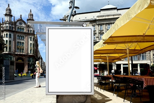 bus shelter at bus stop. white poster ad display space and lightbox. mockup template. blank ad panel. glass design. urban street setting. soft background. people's silhouettes