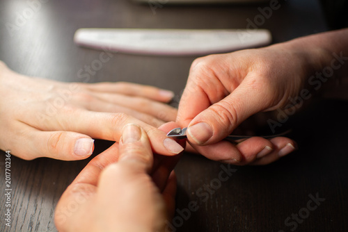 Bild auf Leinwand A manicurist uses cuticle scissors to remove cuticles from nails for a manicure at a beauty salon