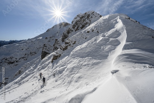 Snow cornices at an embrasure, hikers in the snow at Roggentalsattel, hiking trail to Ammergauer Hochplatte, sun star, in autumn, Ammergau Alps, Bavaria, Germany