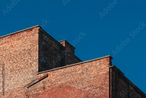 Old red brick industrial building facade under clear blue sky