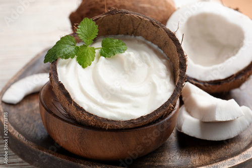 Cuadro en lienzo Tasty coconut yogurt with melissa leaves in shell and nuts on white table, close