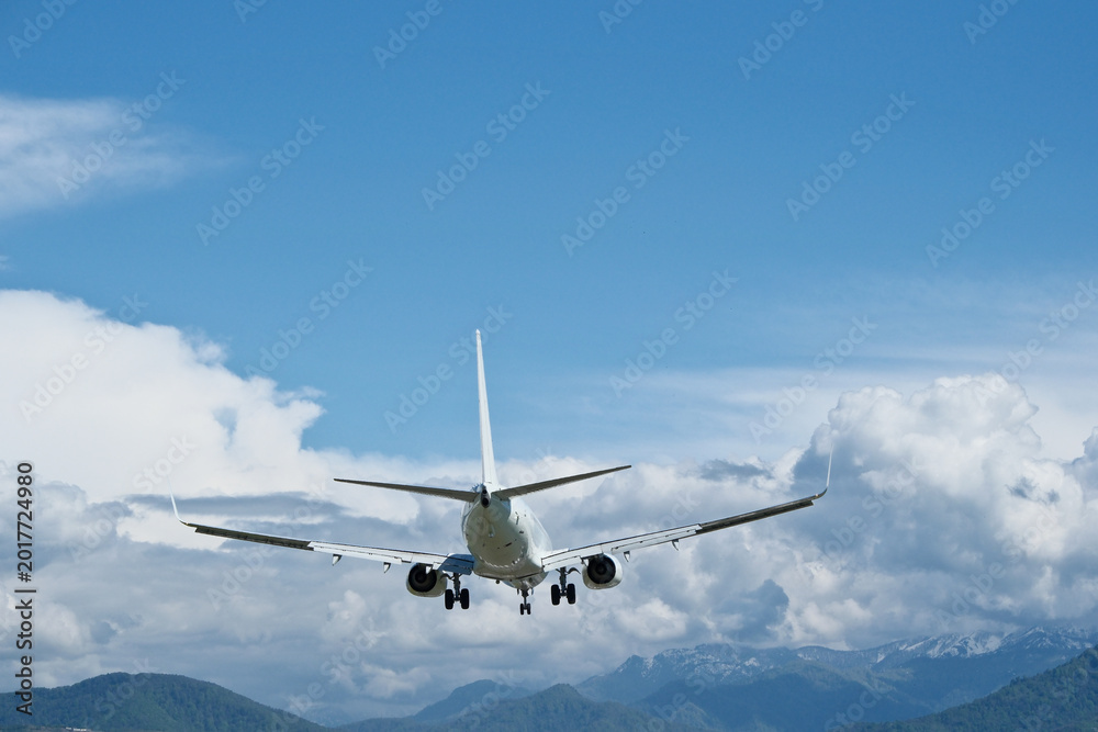 Fototapeta premium White aircraft on final approach against a blue sky with light clouds
