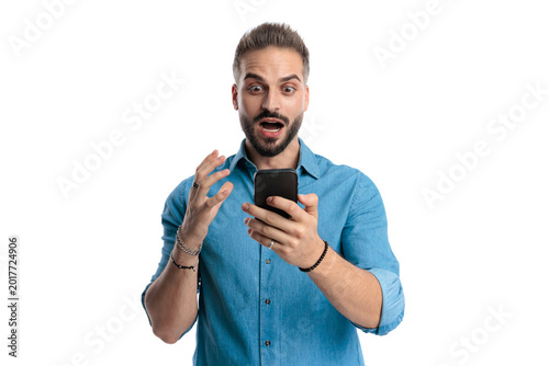 Foto Shocked casual man reading news on smartphone