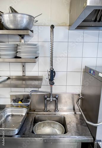 Professional stainless steel dishwashing station in a commercial kitchen with stacked white plates