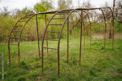 Canvas Print Side view of an abandoned iron monkey bars structure in a rural green area