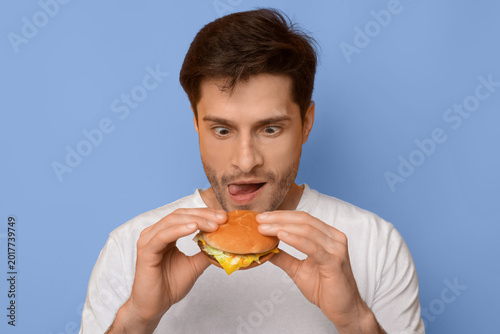 Принти на полотні A man holds a burger in his hands while looking at it with excitement