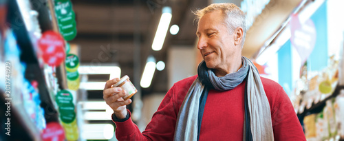 Photography A man is holding a jar while looking at it in a grocery store