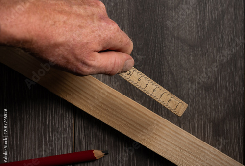 Fotografie Carpenter Measuring Wooden Board With Folding Rule