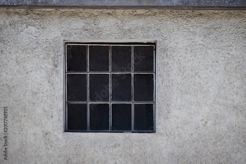 Vintage glass block window in cracked and rough concrete, geometric glass pattern, authentic building surface