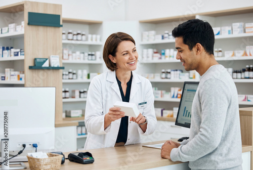 Professional female pharmacist explaining medication to a male customer at a pharmacy counter