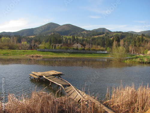 Old ruined wooden pier on a scenic mountain lake background