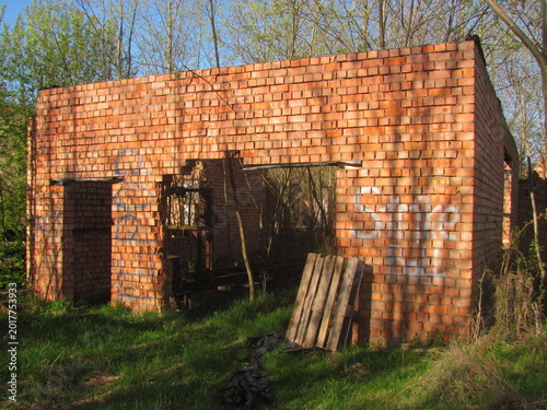 Abandoned red brick industrial ruin overgrown with trees in a rural countryside setting