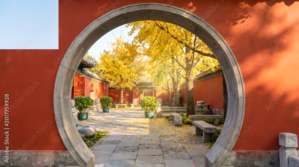 Obraz premium Autumn Chinese garden gate, Circular moon doorway with yellow foliage, Traditional red wall and stone path, Serene courtyard travel scene