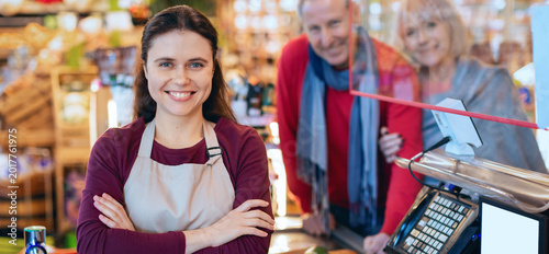 Cuadro en lienzo A shopkeeper stands at the register with a smile while customers look on