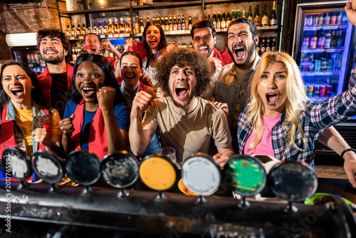 Group of friends cheering during live sports match in pub