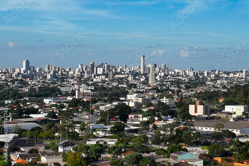 General drone view of the city of Cascavel, western region of Parana, showing the buildings, houses, and wooded areas on a slightly sunny day.