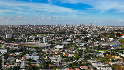 General drone view of the city of Cascavel, western region of Parana, showing the buildings, houses, and wooded areas on a slightly sunny day.