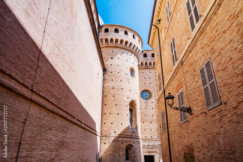 Street view capturing the old brick walls of traditional buildings along Corso Traiano Boccalini in Loreto, Marches, Italy, leading towards the fortified Basilica della Santa Casa