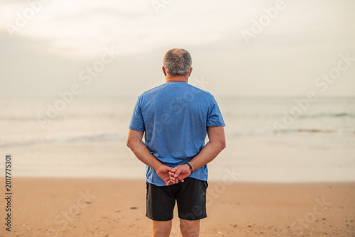 Senior man standing on beach practicing active wellness